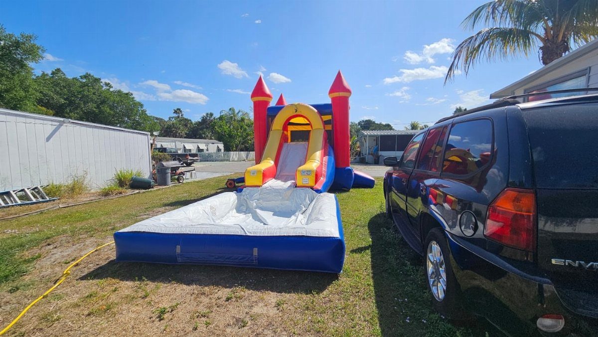 Inflatable water slide with red turrets and blue splash pool on a lawn