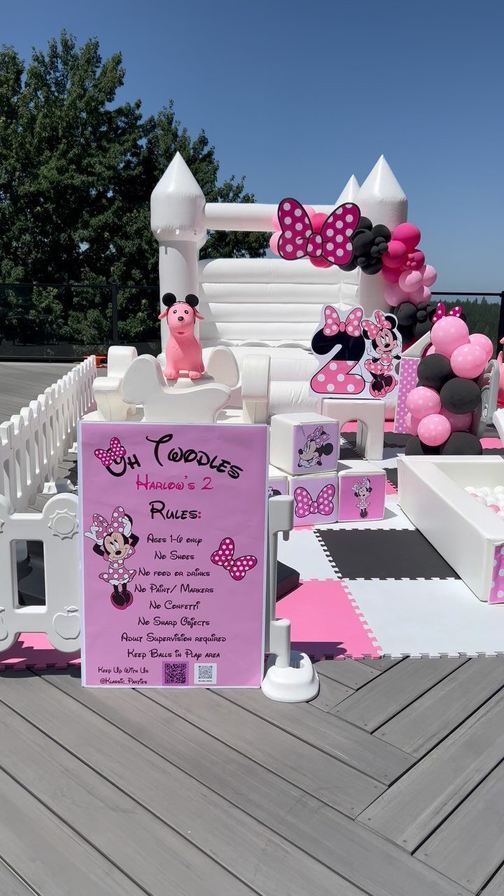 White inflatable bounce house castle with pink and black Minnie Mouse decorations outdoors.
