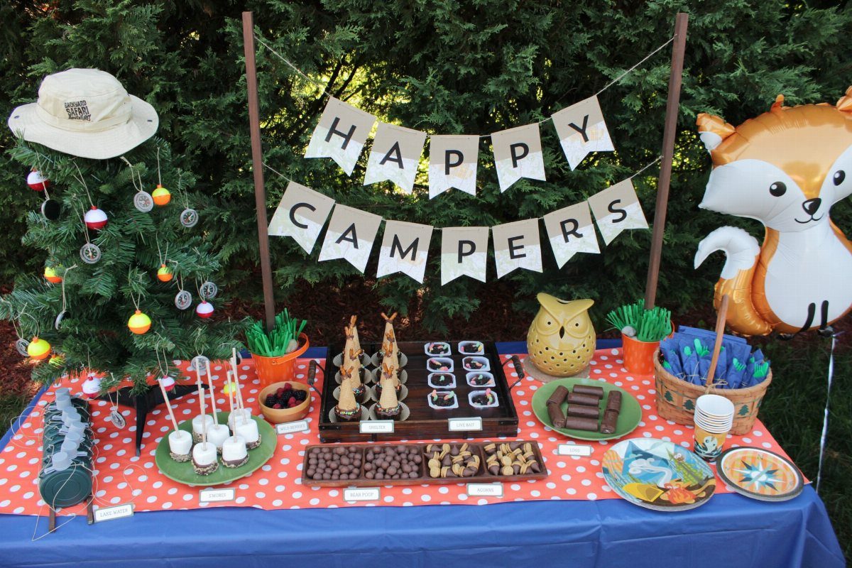 Camping party table with Happy Campers banner, treats, and a fox balloon.
