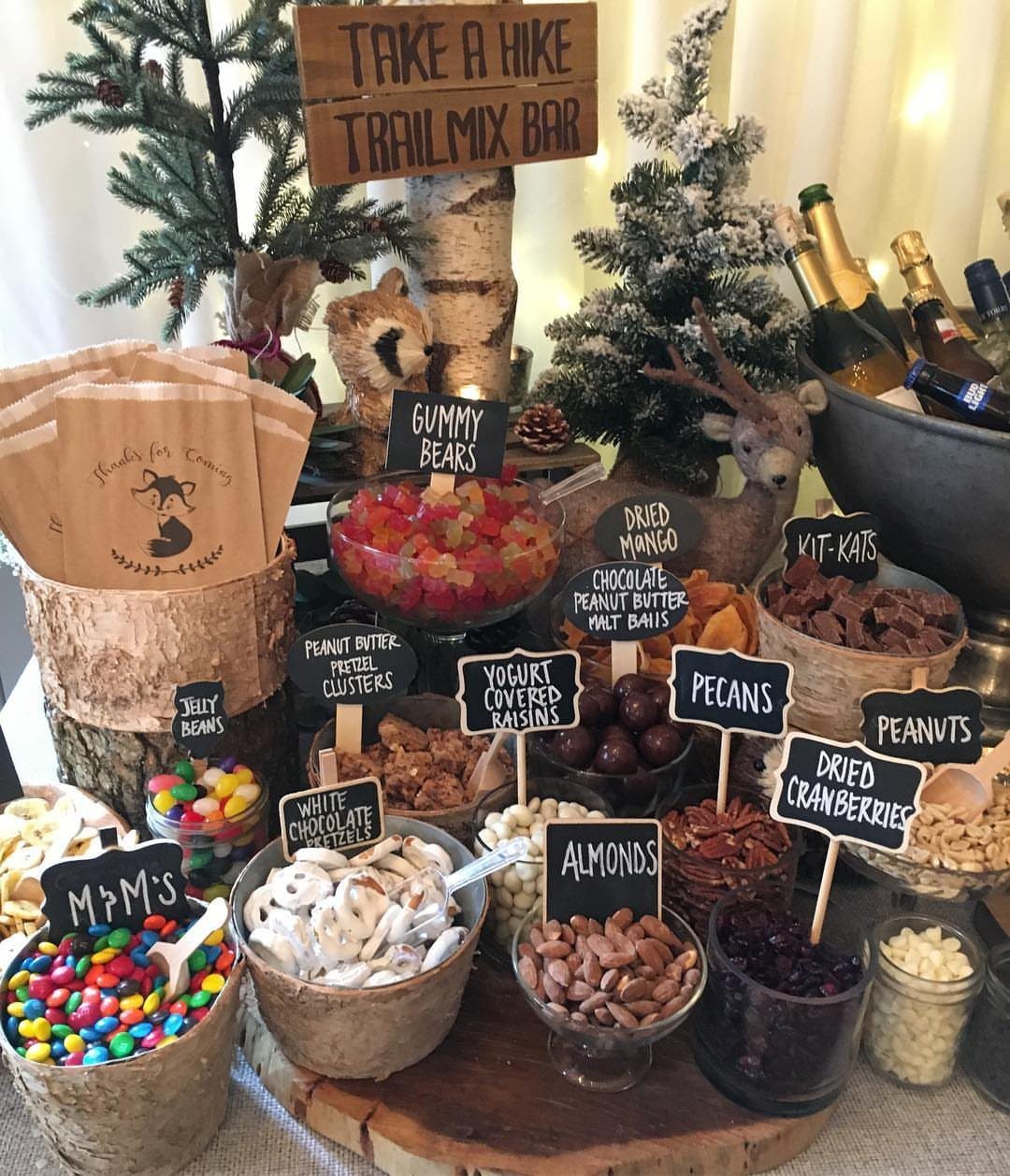 Trail mix bar with labeled bowls of nuts and candies under a wooden sign.