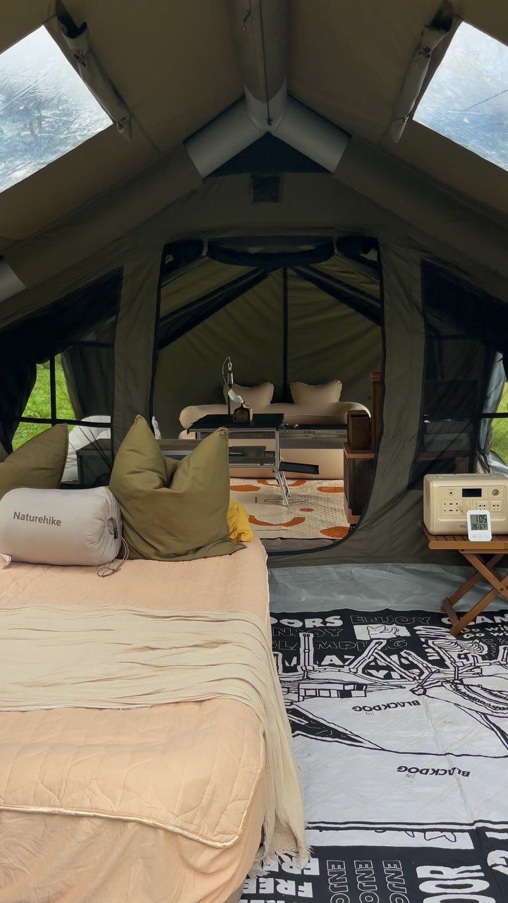 Luxurious glamping tent interior with comfortable beds, pillows, and a patterned floor rug.