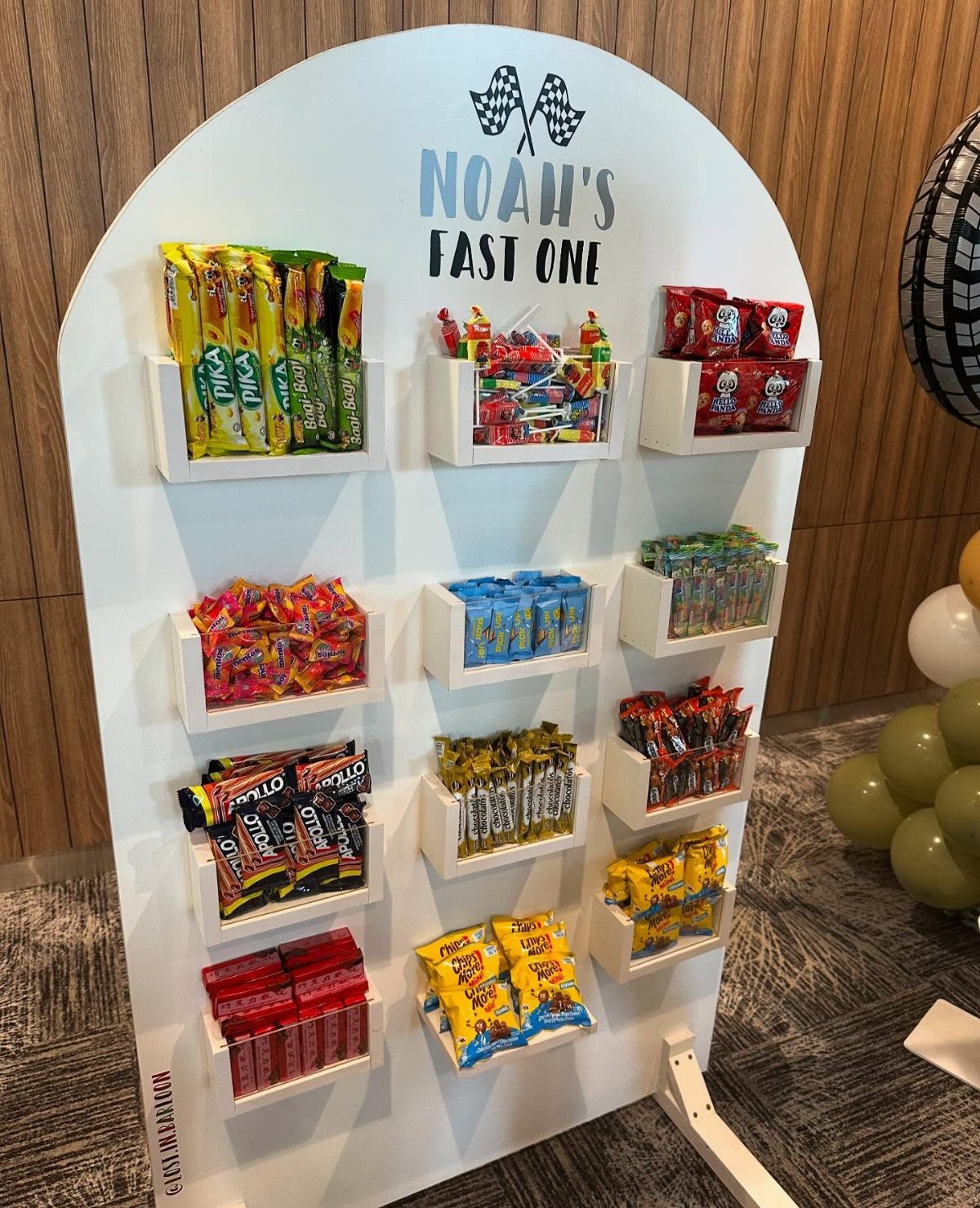 White arched candy wall display with shelves of colorful sweets and racing theme text.