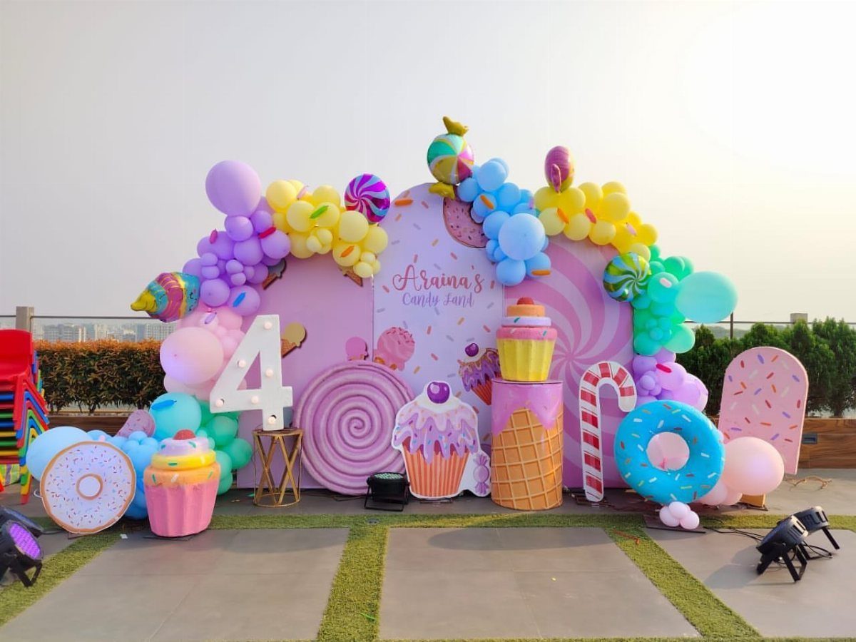 Colorful birthday party setup with giant candy props and pastel balloons.