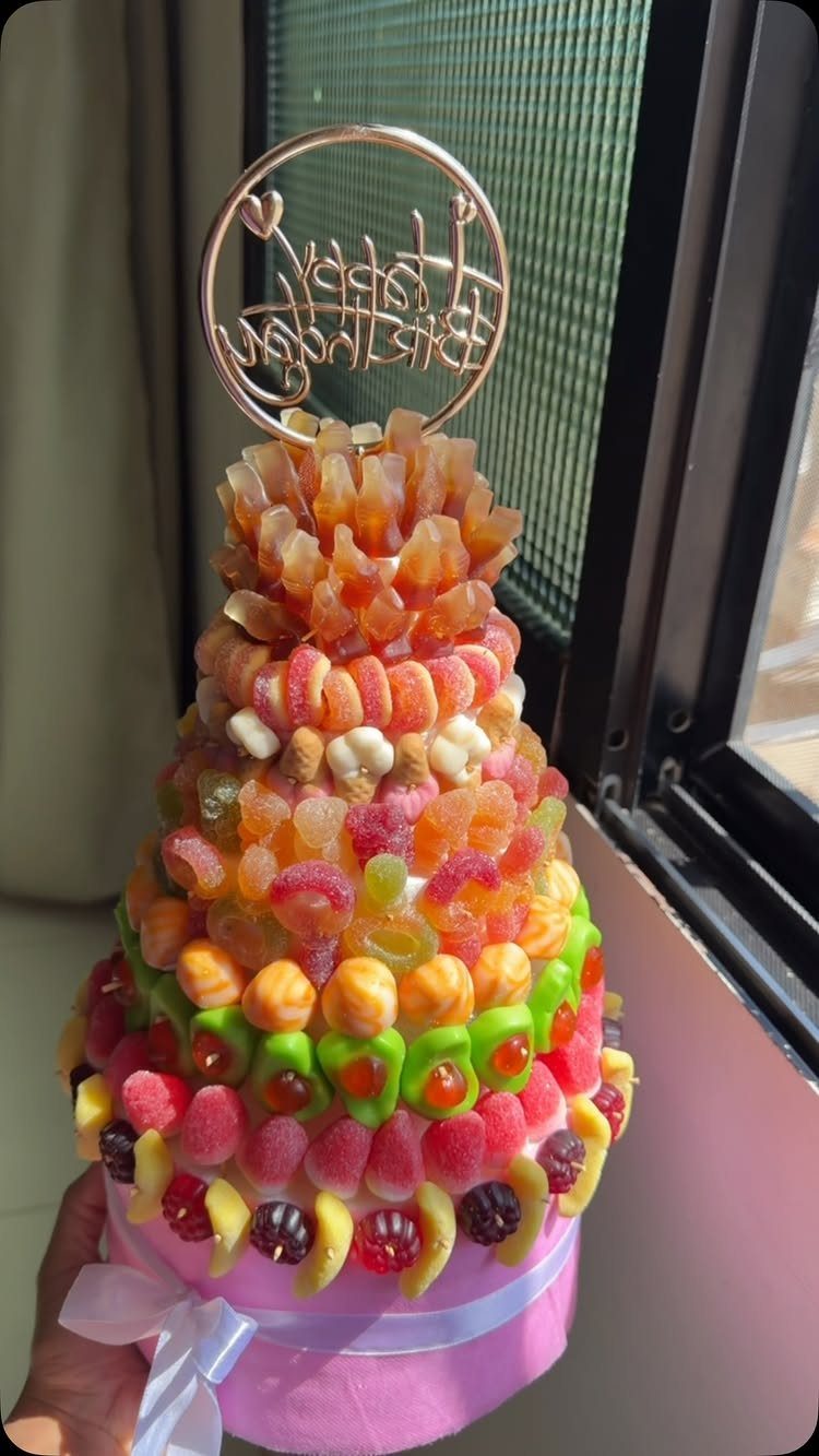 Colorful gummy candy tower on a pink base with a gold topper.