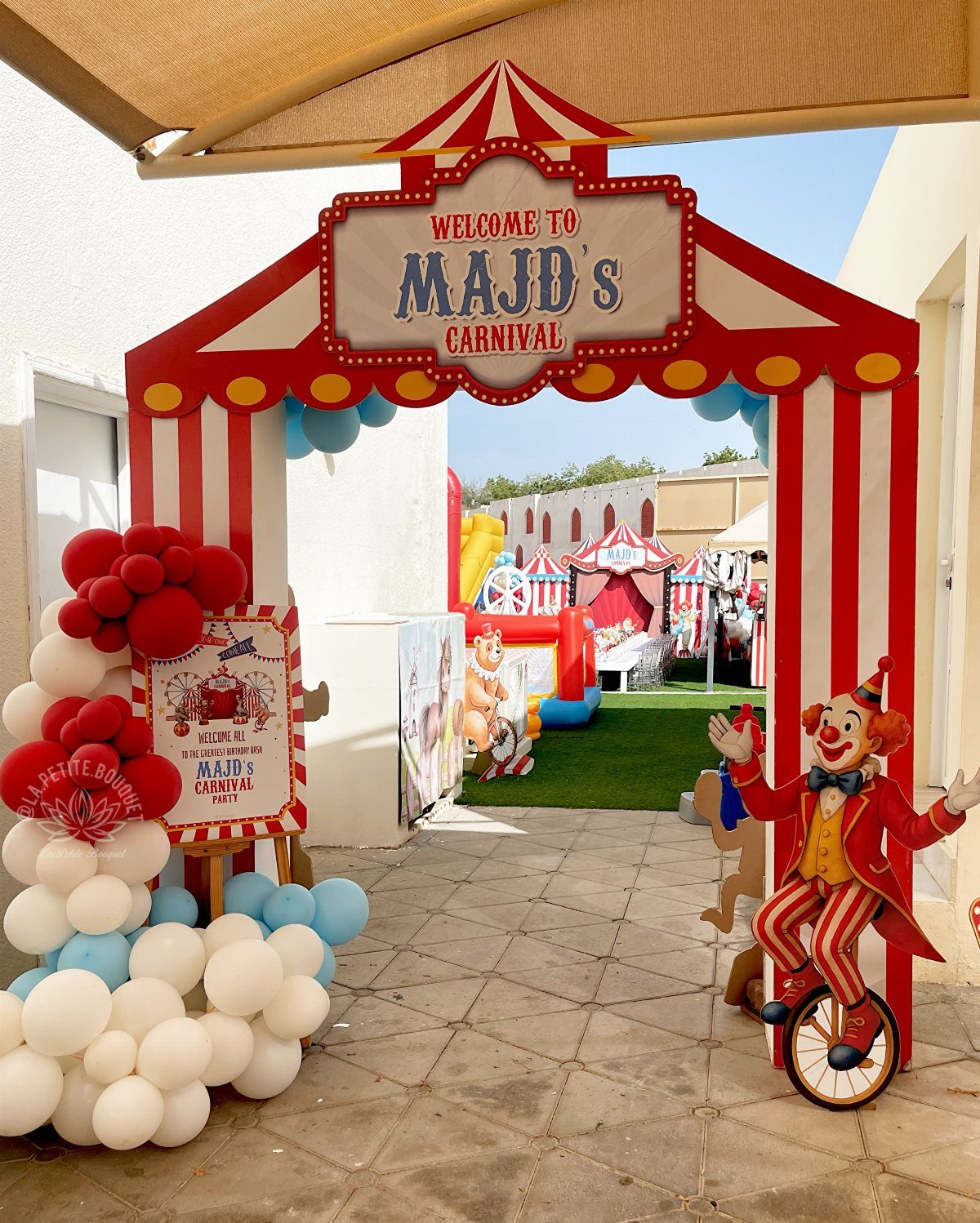 Carnival themed party entrance with red and white striped arch and clown cutout