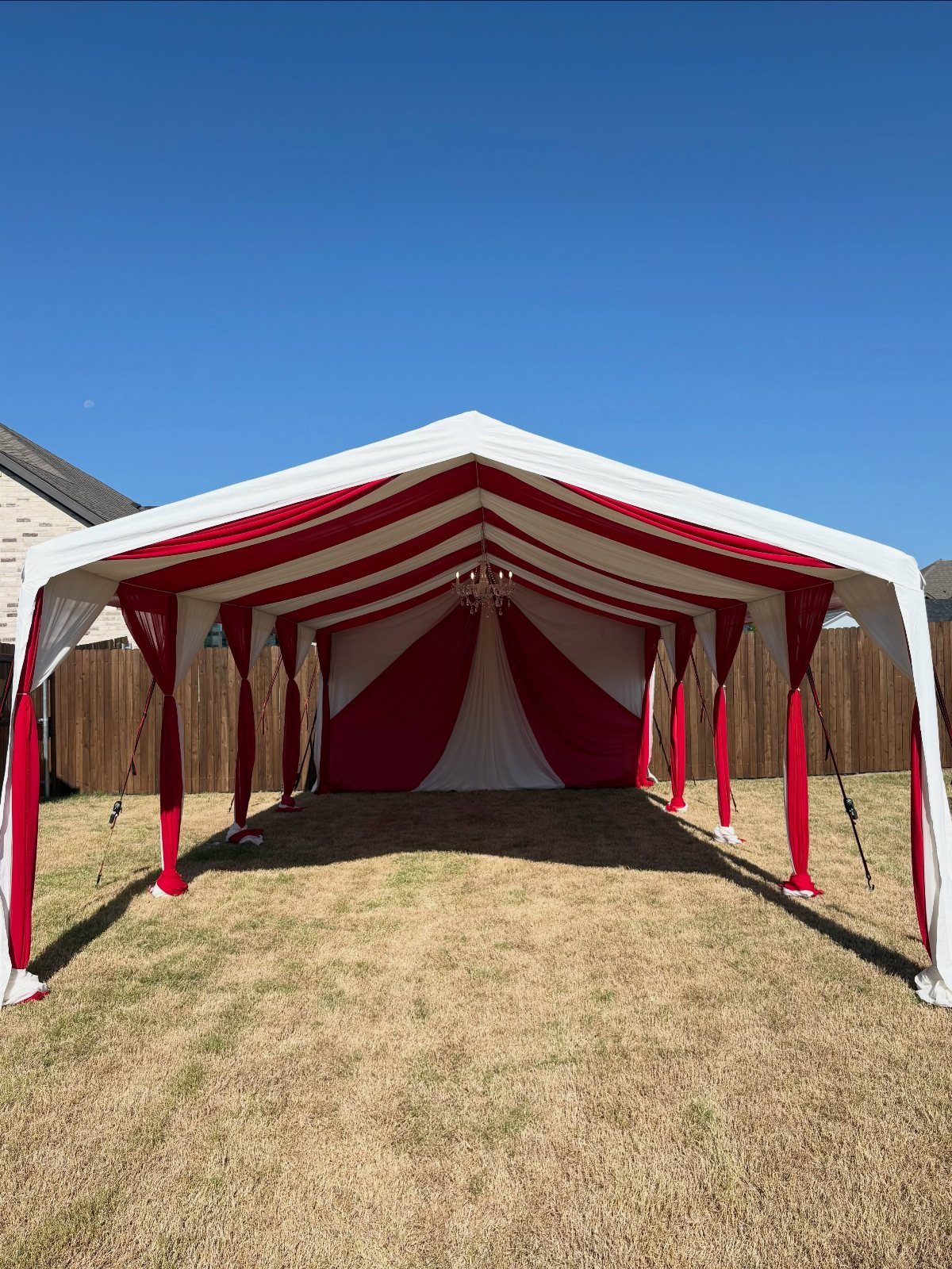 Red and white striped circus tent set up on a grassy outdoor lawn