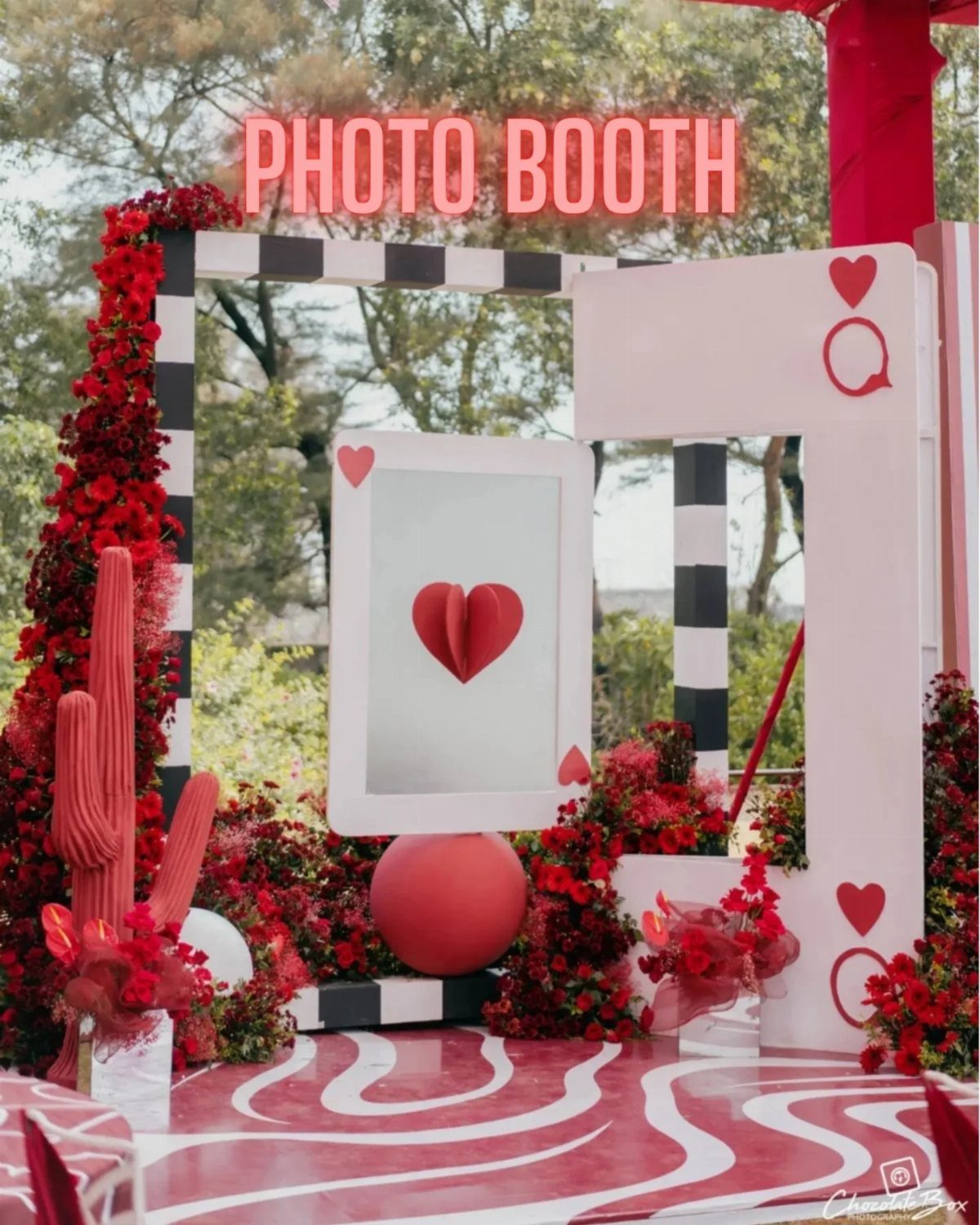 Red and white photo booth setup with heart decorations and neon signage outdoors.