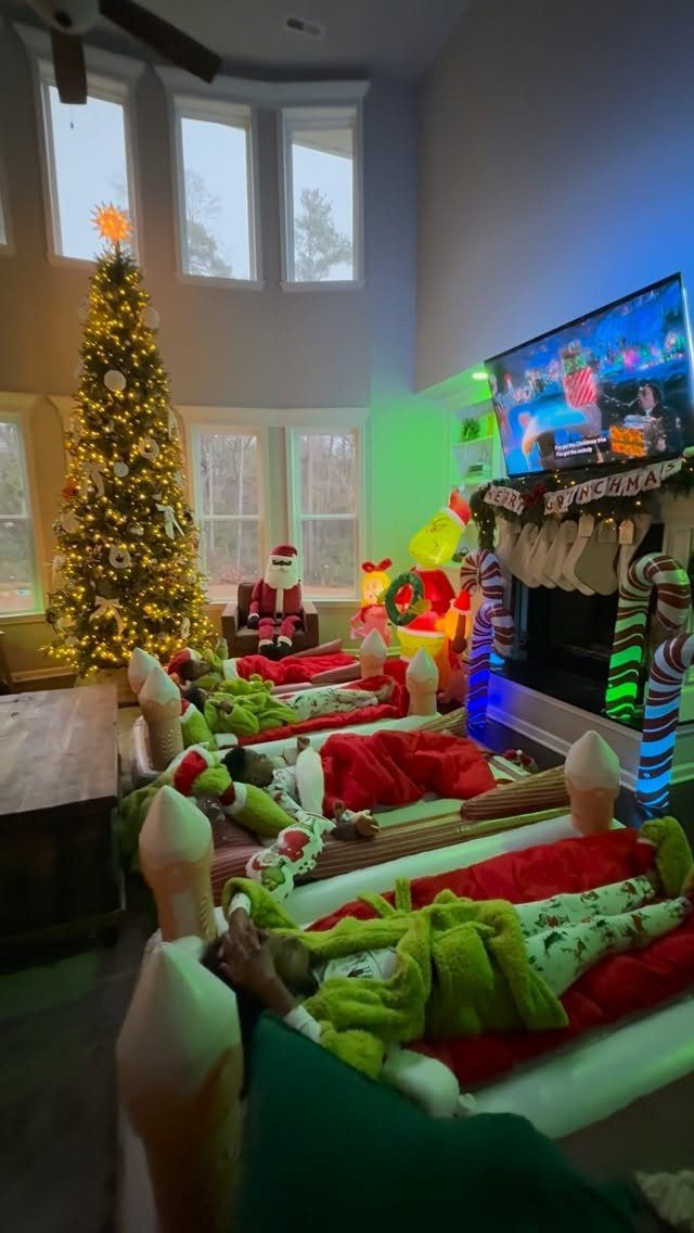 Christmas tree and fireplace next to several air mattresses with festive holiday bedding.