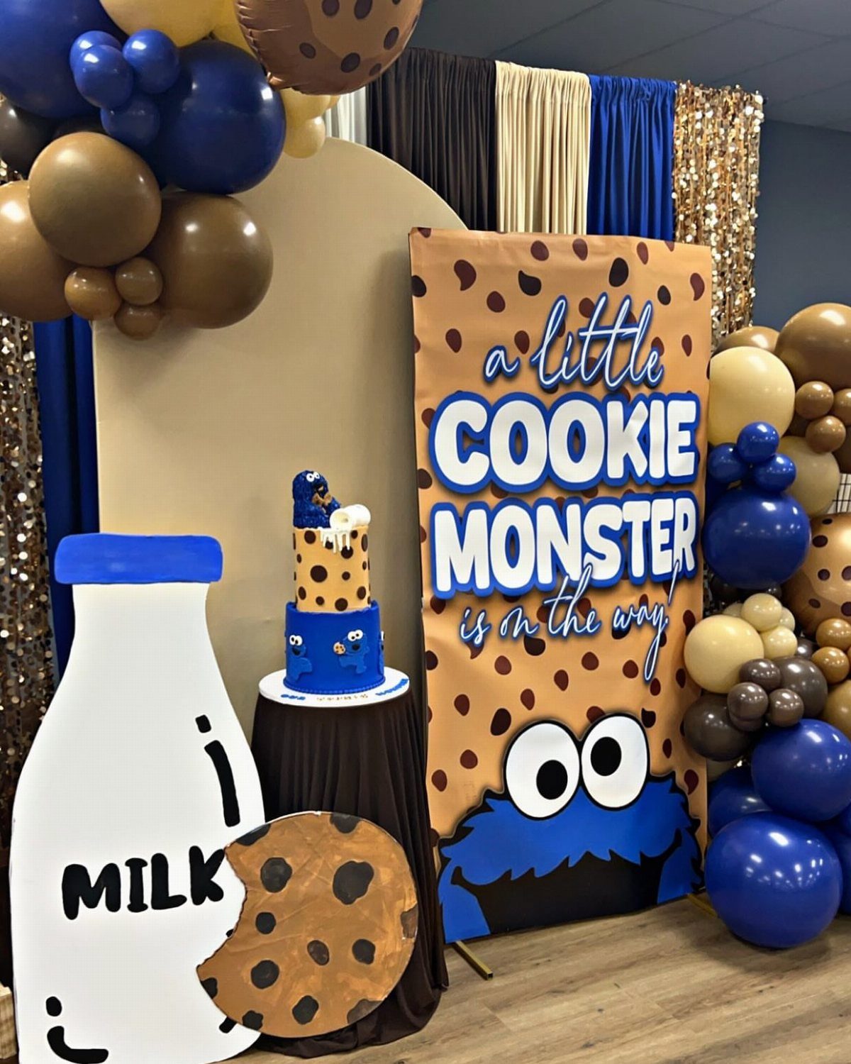 Cookie Monster party decorations with a themed banner, cake, balloons, and milk cutout.