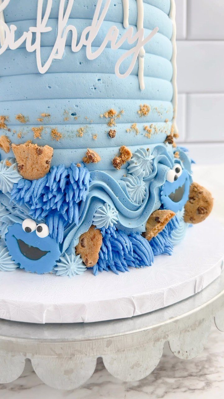 Blue tiered birthday cake decorated with Cookie Monster faces and chocolate chip cookies.