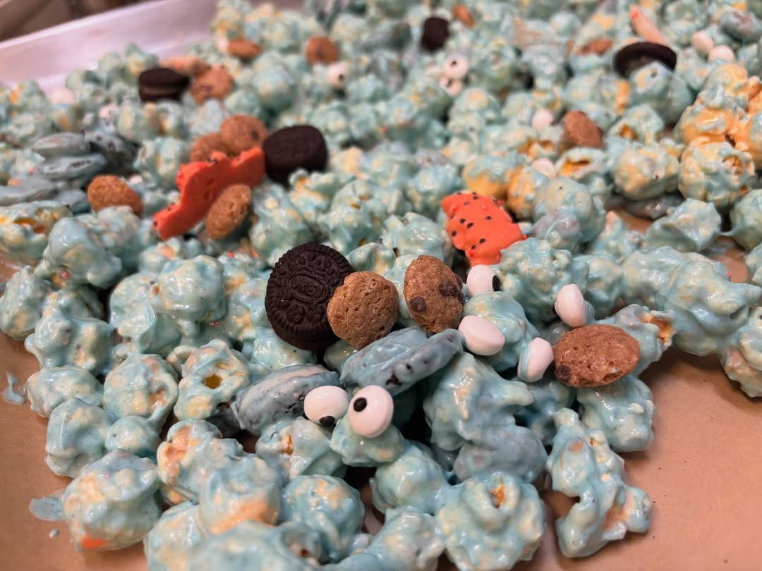 Blue coated popcorn mixed with mini cookies and candy eyes on a tray.