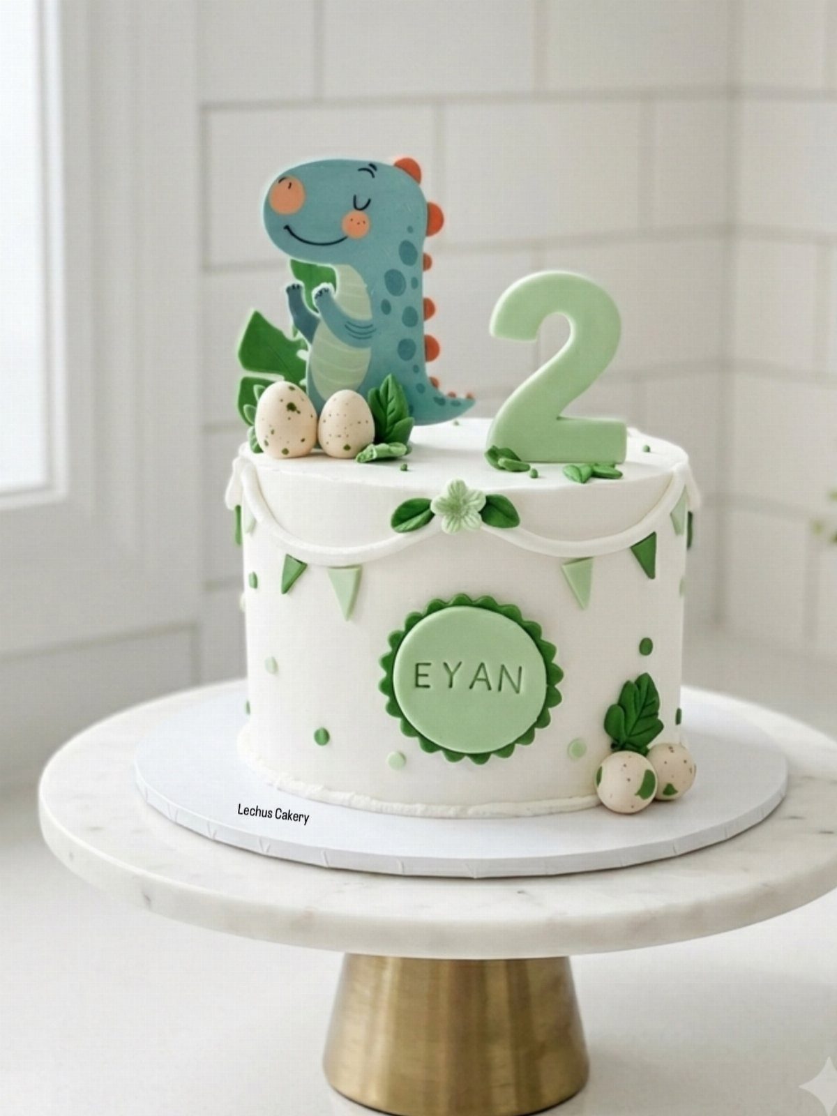 White birthday cake with a blue cartoon dinosaur topper and green number two.