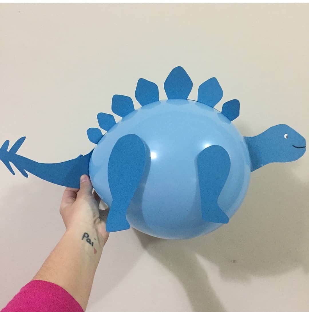 Blue balloon stegosaurus with cardstock plates, head, and tail held by a hand.