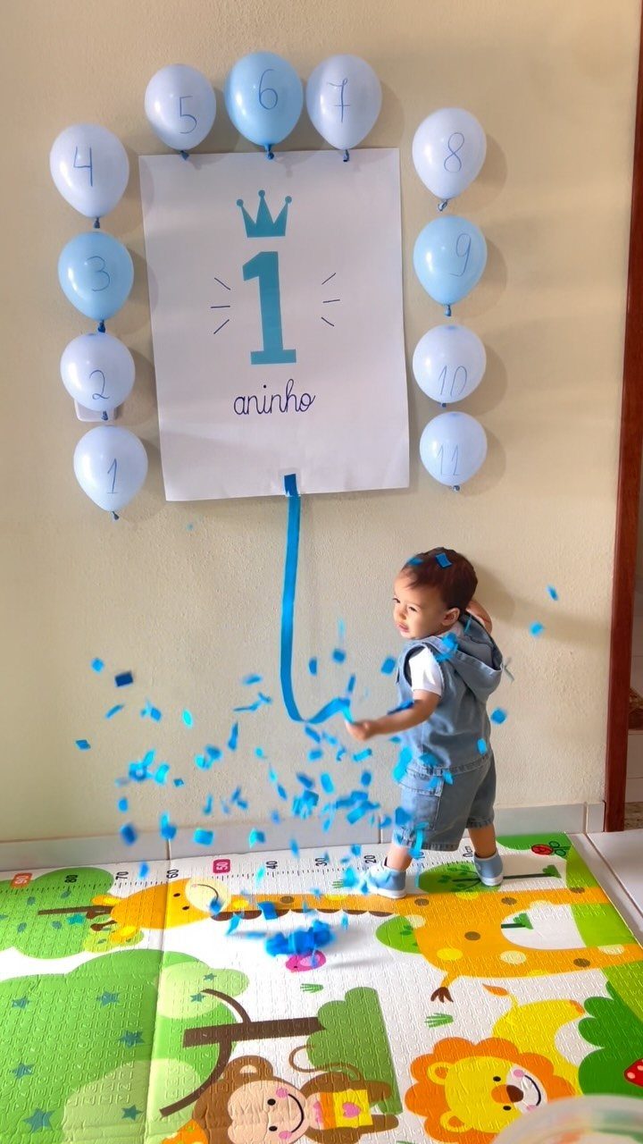 Toddler boy pulling a ribbon to release blue confetti at a first birthday party