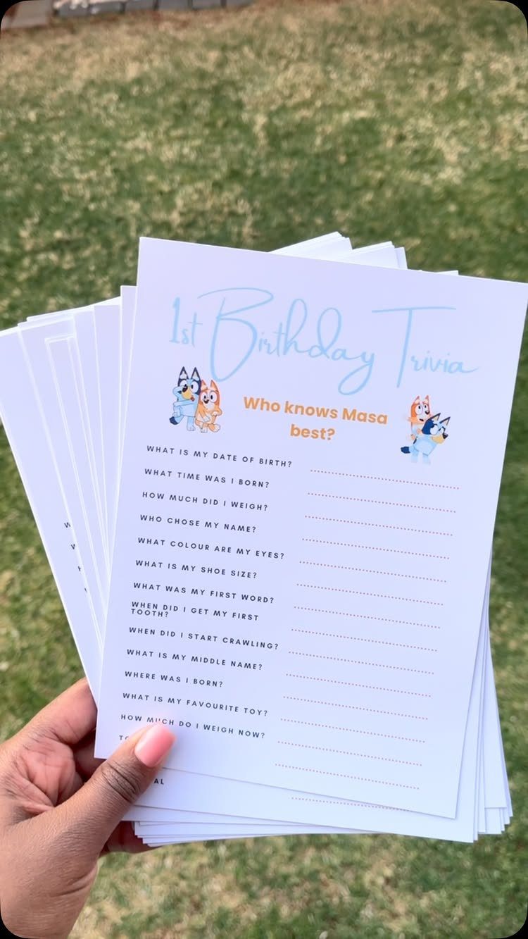 Trivia sheets for a first birthday party held over a green grass lawn.