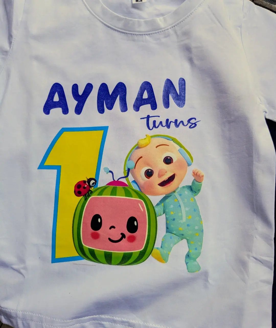 White birthday t-shirt with Ayman turns 1 text and cartoon characters