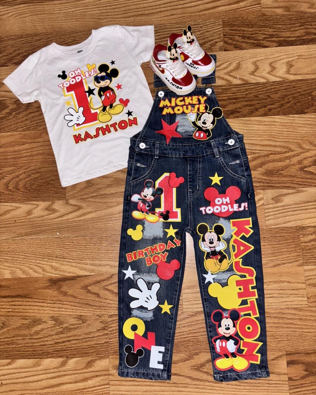 Mickey Mouse themed first birthday outfit with denim overalls and white t-shirt.