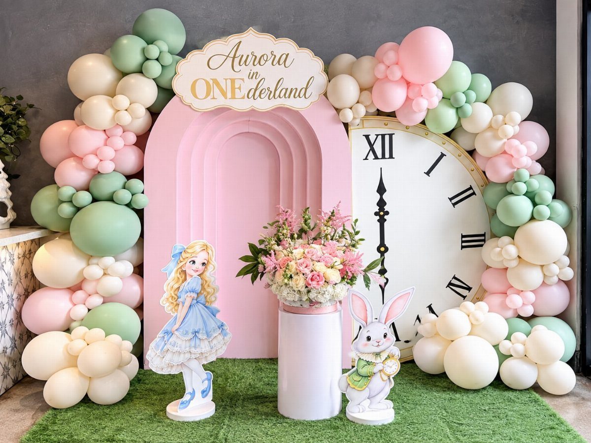 Alice in Wonderland themed birthday setup with pastel balloons, large clock, and cutouts.