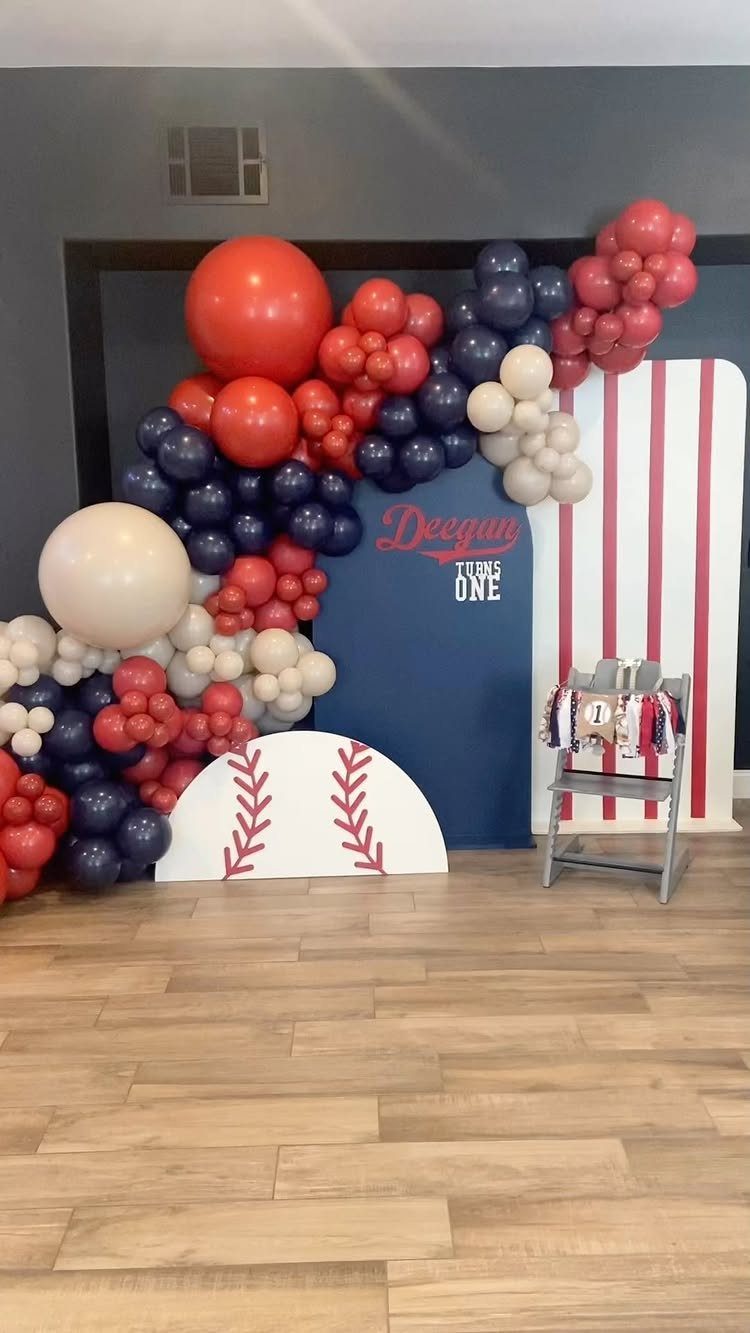 Baseball themed first birthday party decor with red, white, and navy balloons.