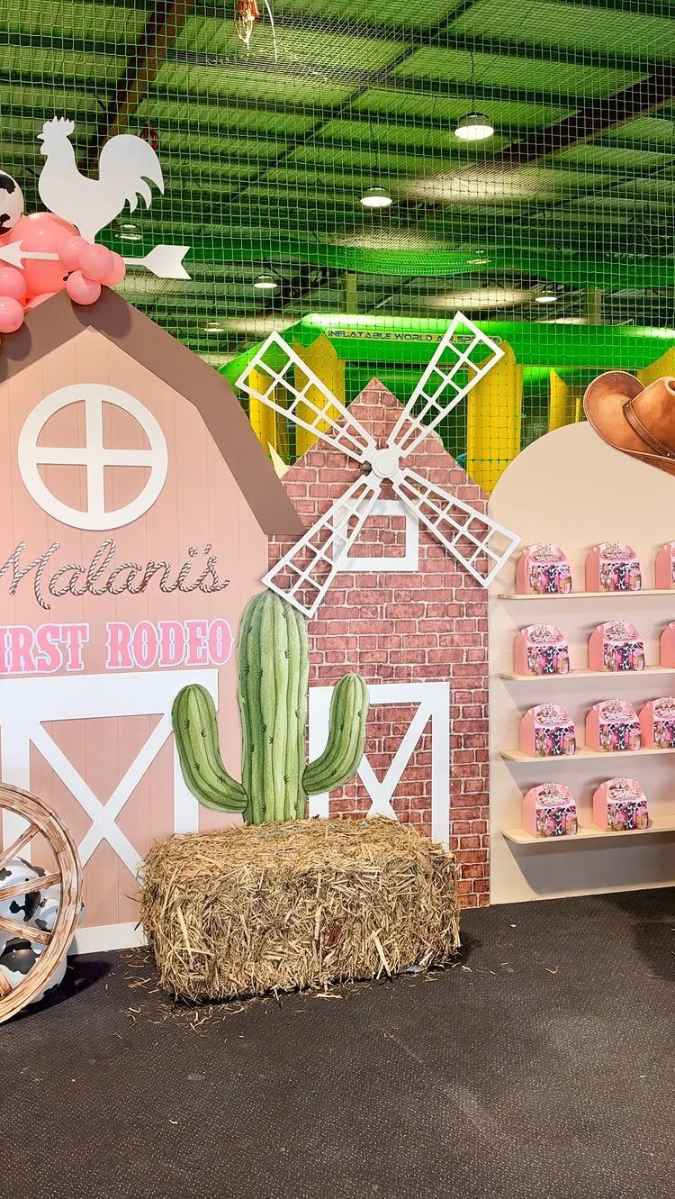 Western party backdrop with a barn, windmill, cactus, and a hay bale.