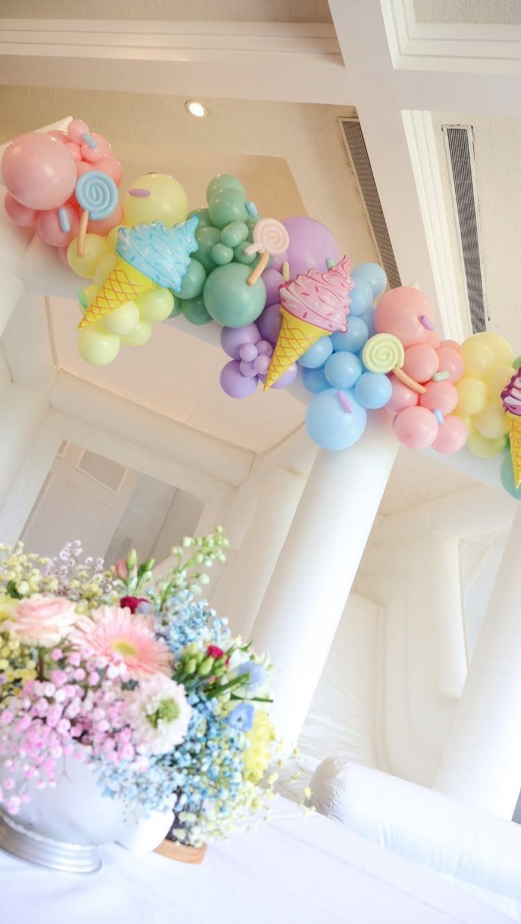 Pastel balloon garland with ice cream shapes and a colorful floral bouquet.
