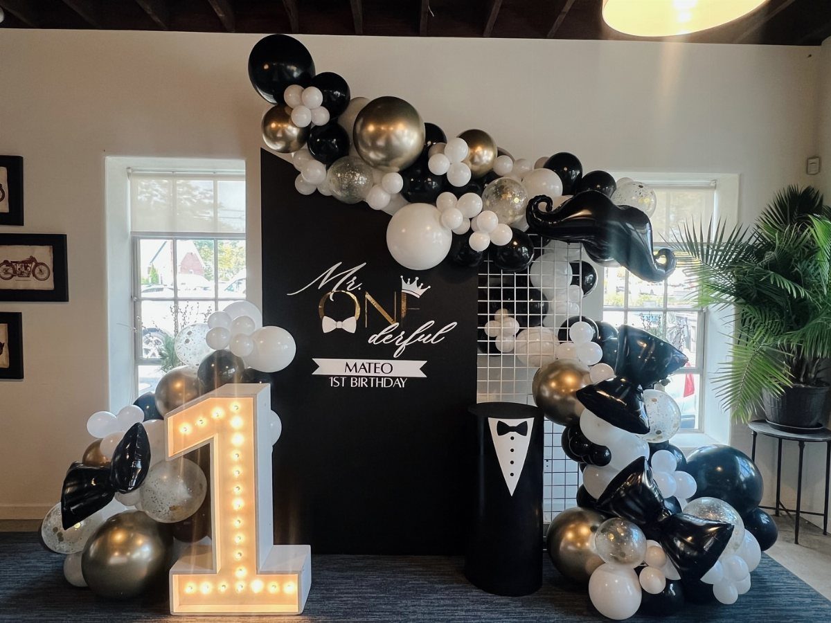 Black, white, and gold birthday decorations with a large lit number one.