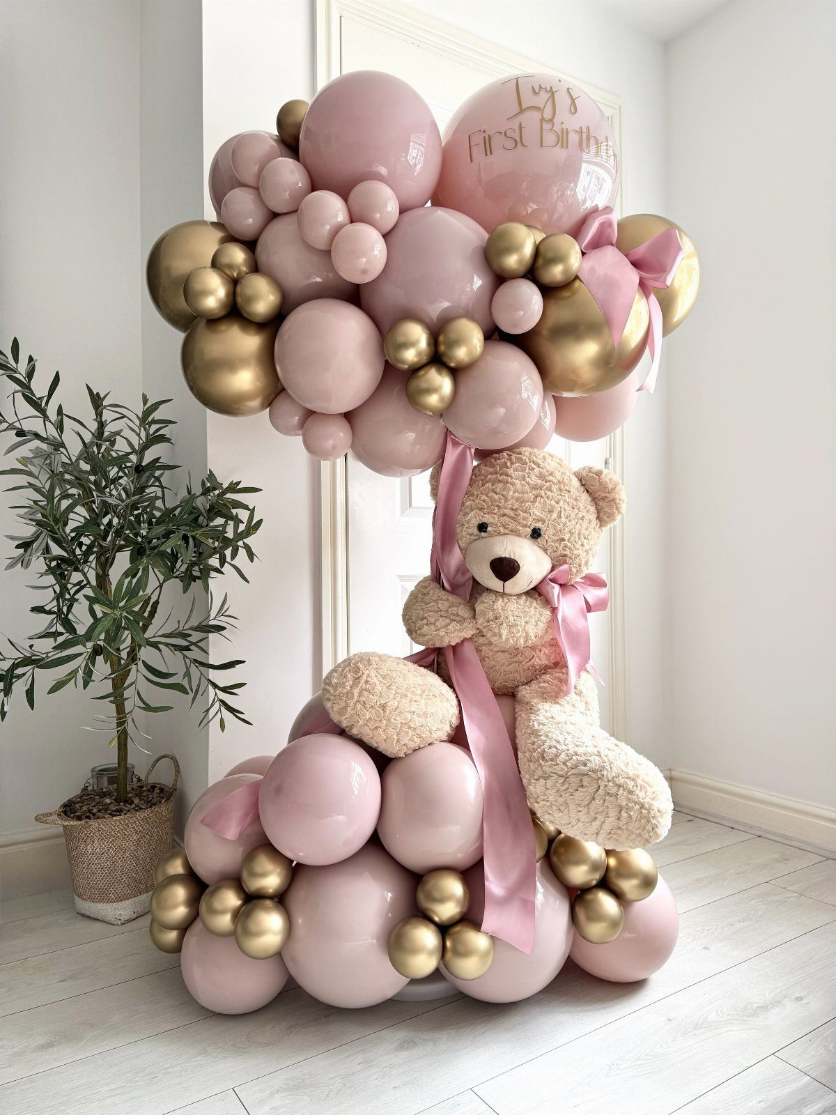 Number one balloon arrangement in pink and gold with a teddy bear.