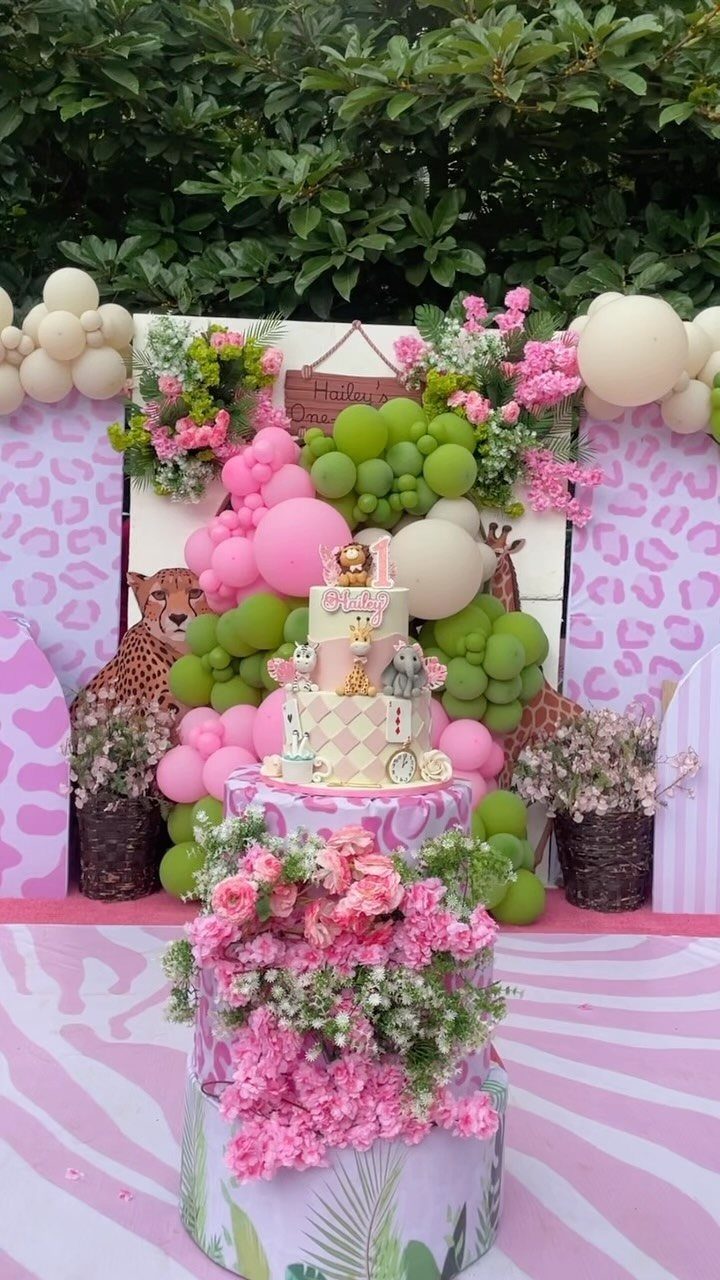Birthday party setup with pink and green balloons, flowers, and a cheetah statue.