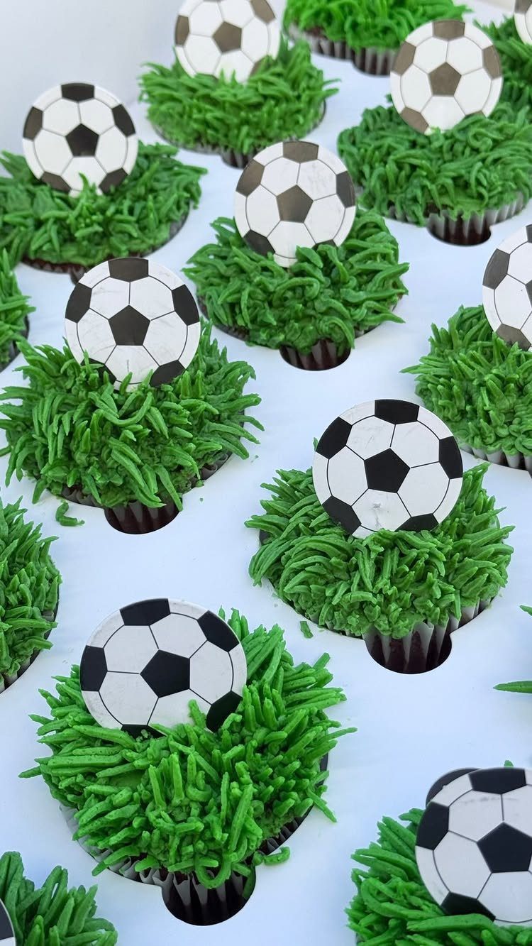 Cupcakes with green grass frosting and soccer ball toppers on a white background