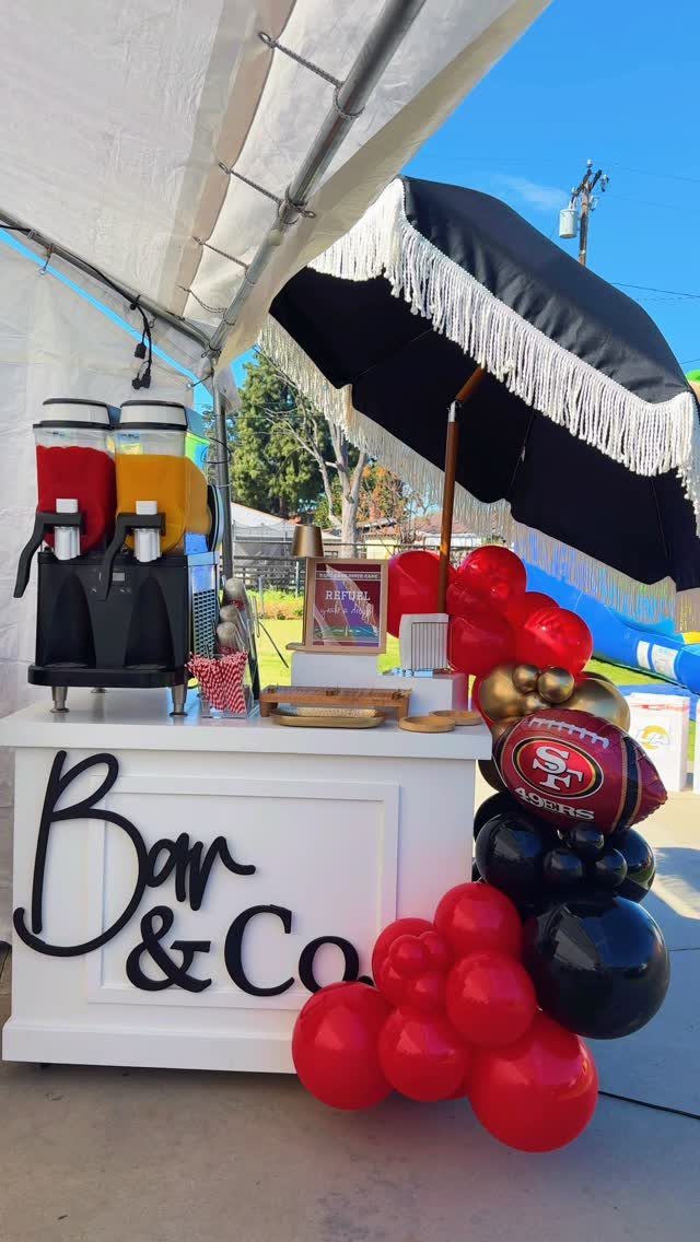 Football themed party bar with red and black balloons and a 49ers football.