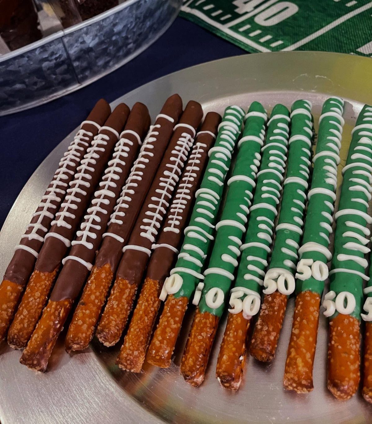 Chocolate covered pretzel rods decorated as footballs and green football fields on a platter
