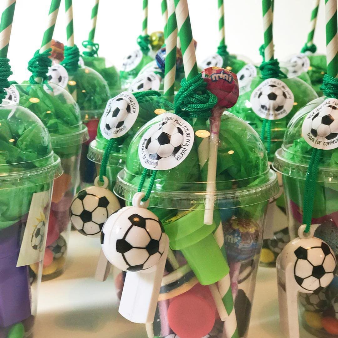 Clear plastic party cups filled with candy and soccer ball charms for guests.