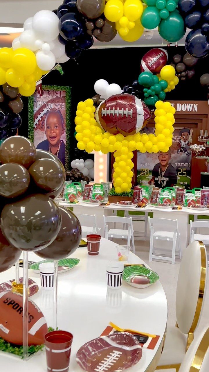 Football themed birthday party decorations with balloons, trophy, and themed table settings.