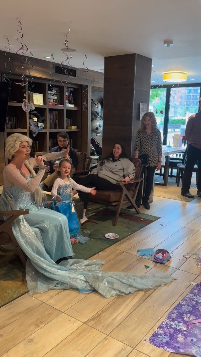 Elsa entertainer interacting with a young girl in a blue dress at a party
