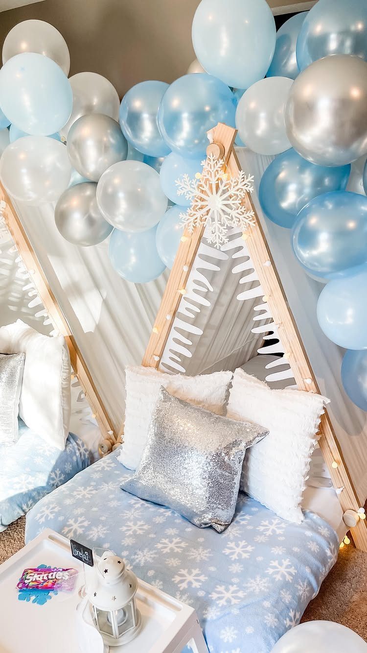 Wooden A-frame teepee bed with snowflake bedding and blue and silver balloons.