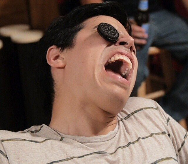 Young man tilting head back to move a cookie from forehead to mouth