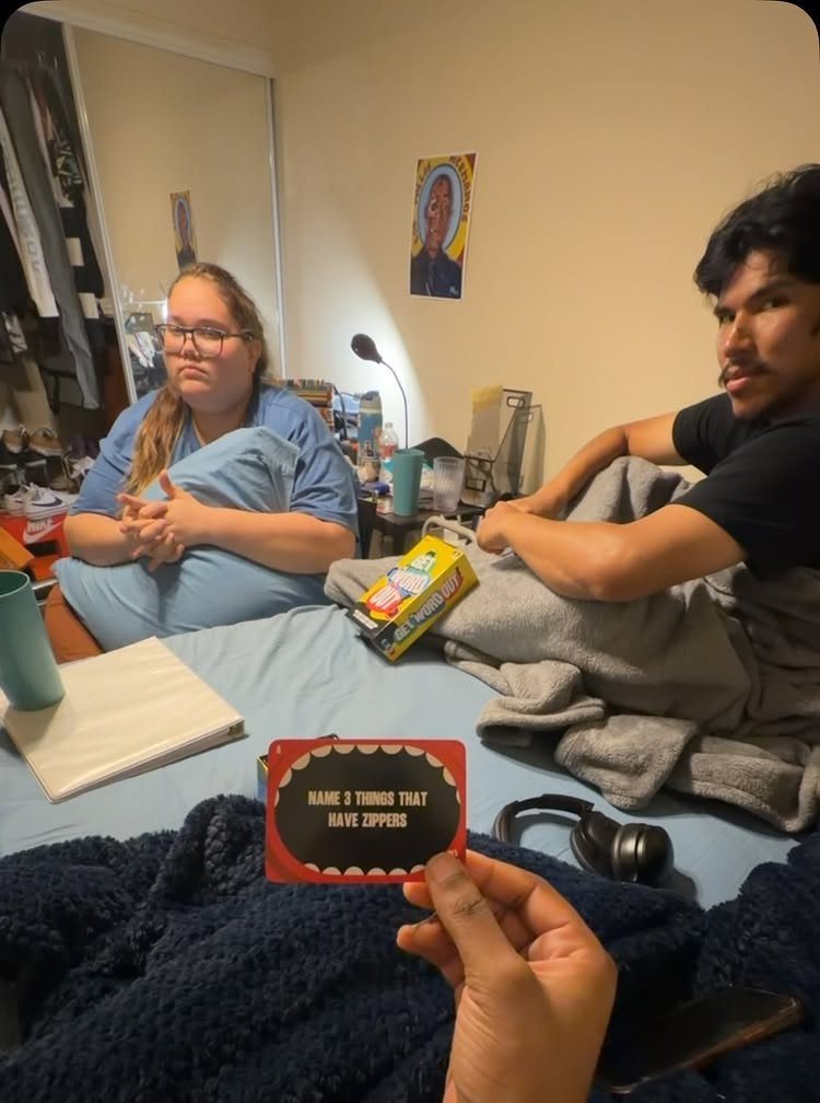 Two people on a bed with a person holding a red game card.