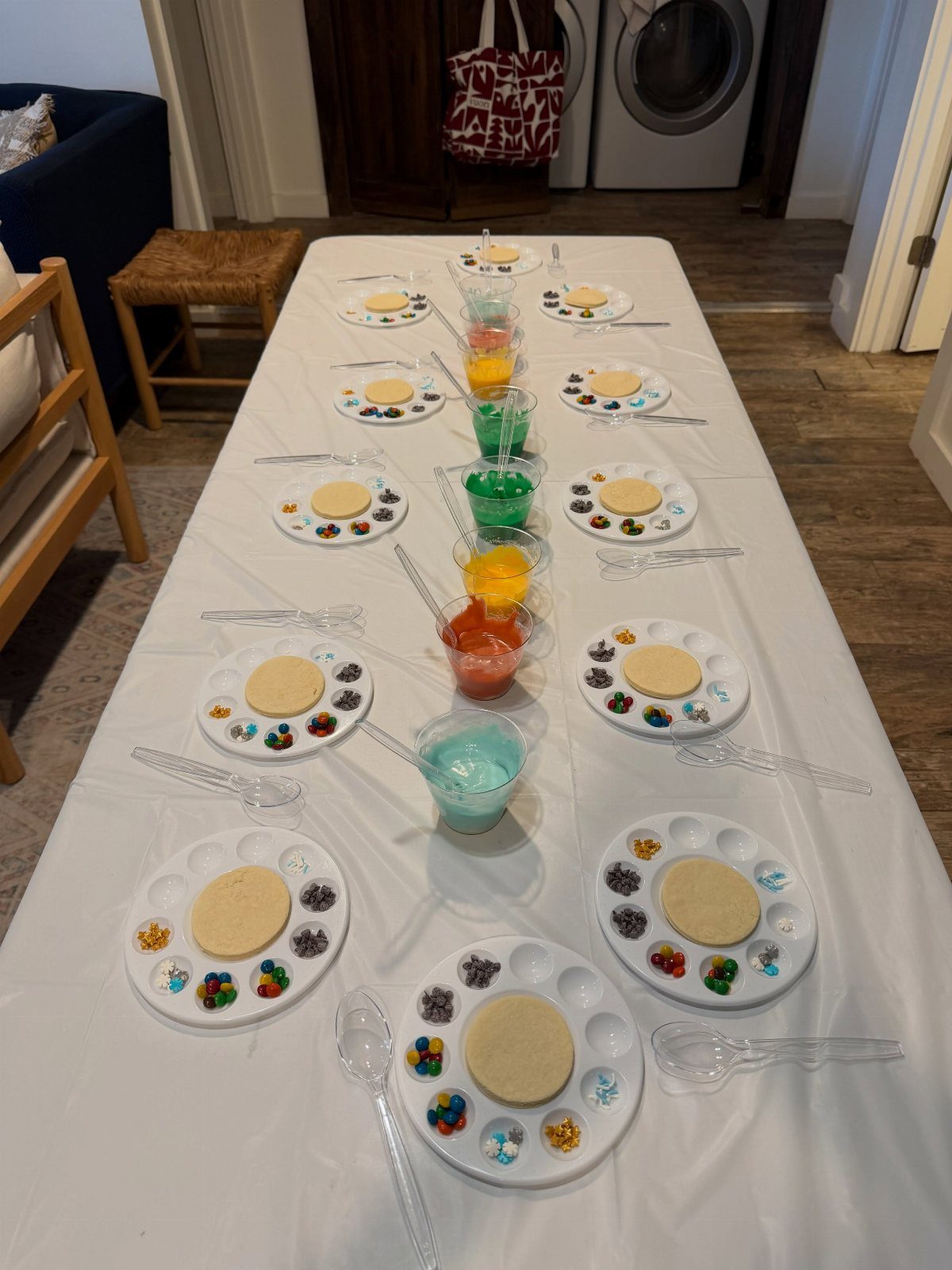 Cookie decorating station with plain cookies, colorful sprinkles, and icing on a table.