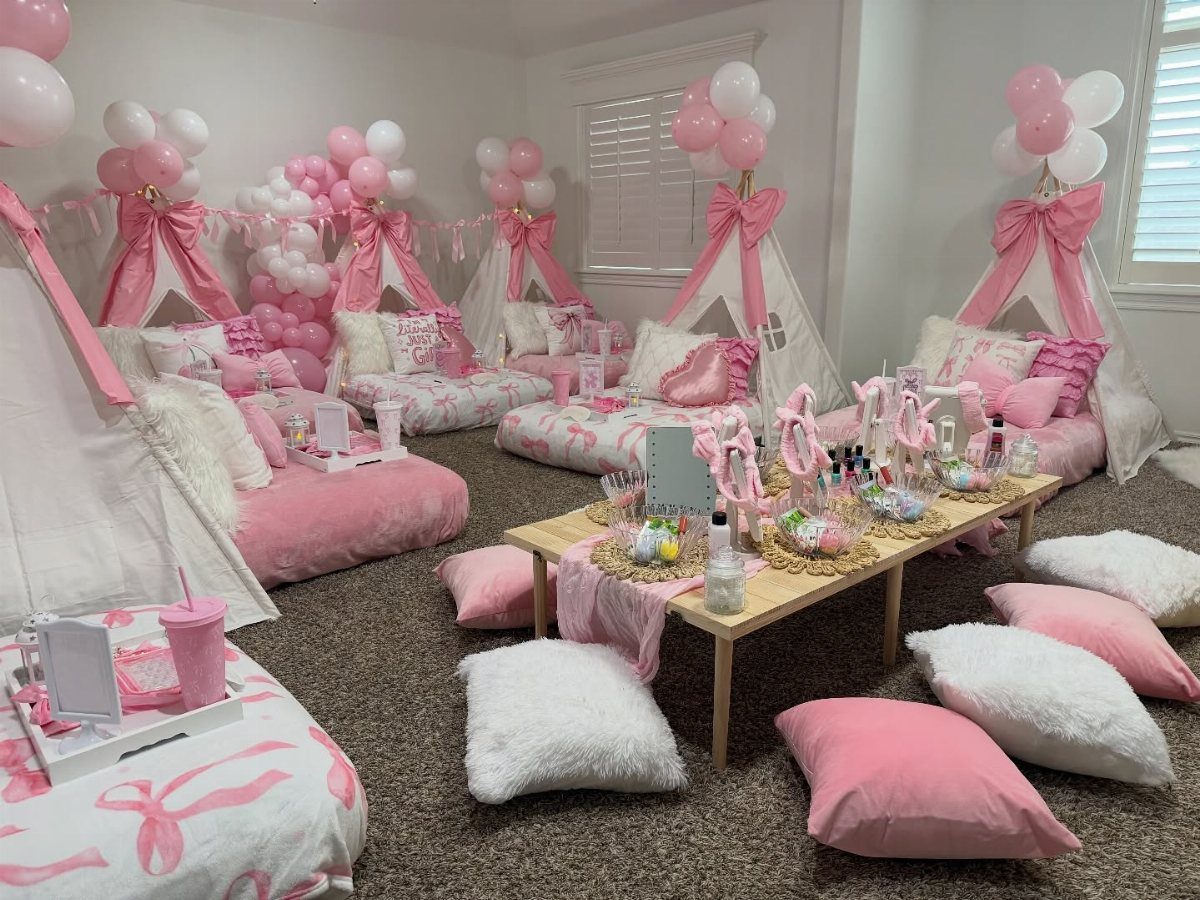 Pink and white sleepover setup with teepees, balloons, and a beauty product station.