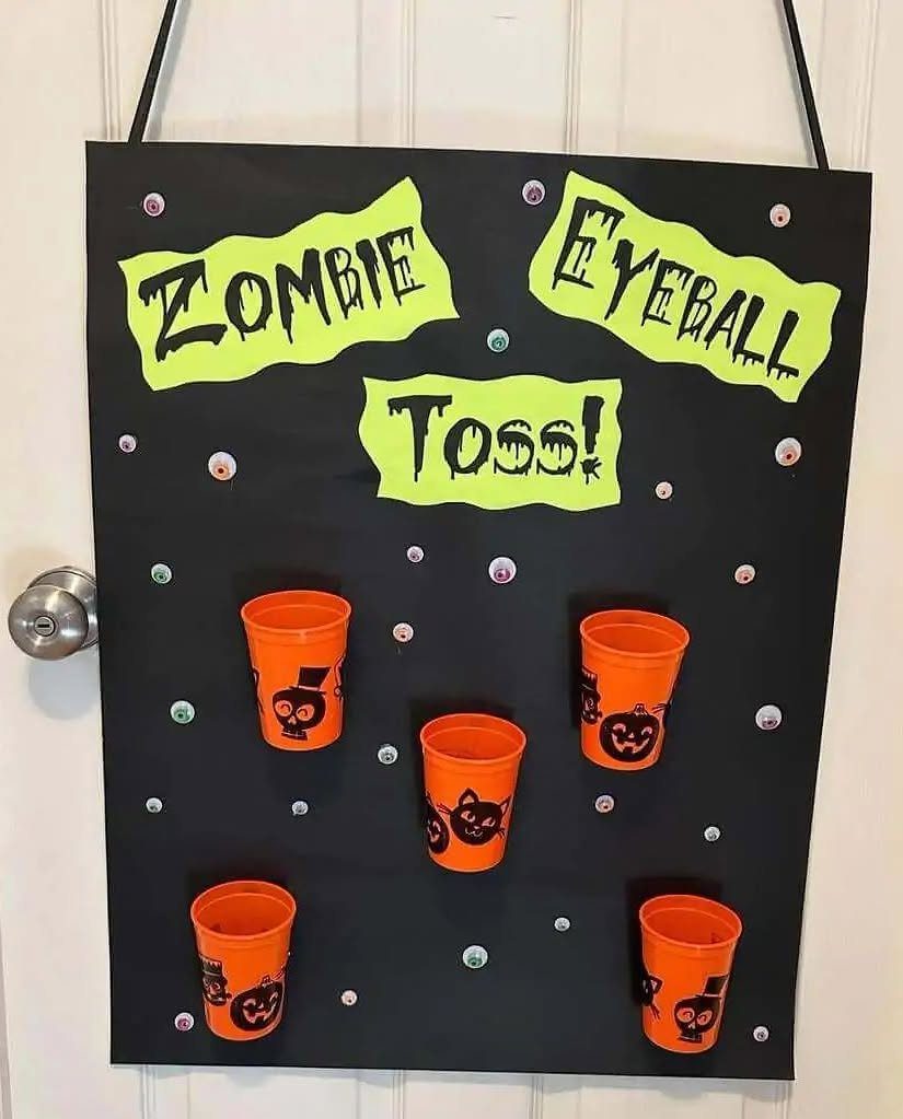 Zombie Eyeball Toss game with orange cups on a black hanging board.