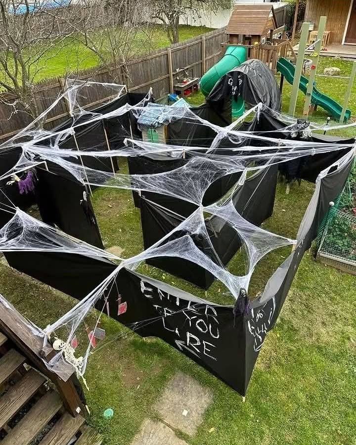 Black fabric maze with white spider webs in a backyard for Halloween.