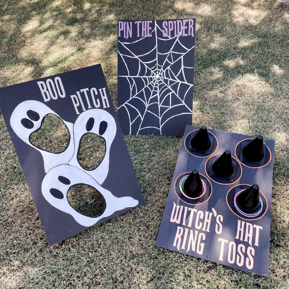 Three handmade Halloween carnival games including a witch hat ring toss on grass.