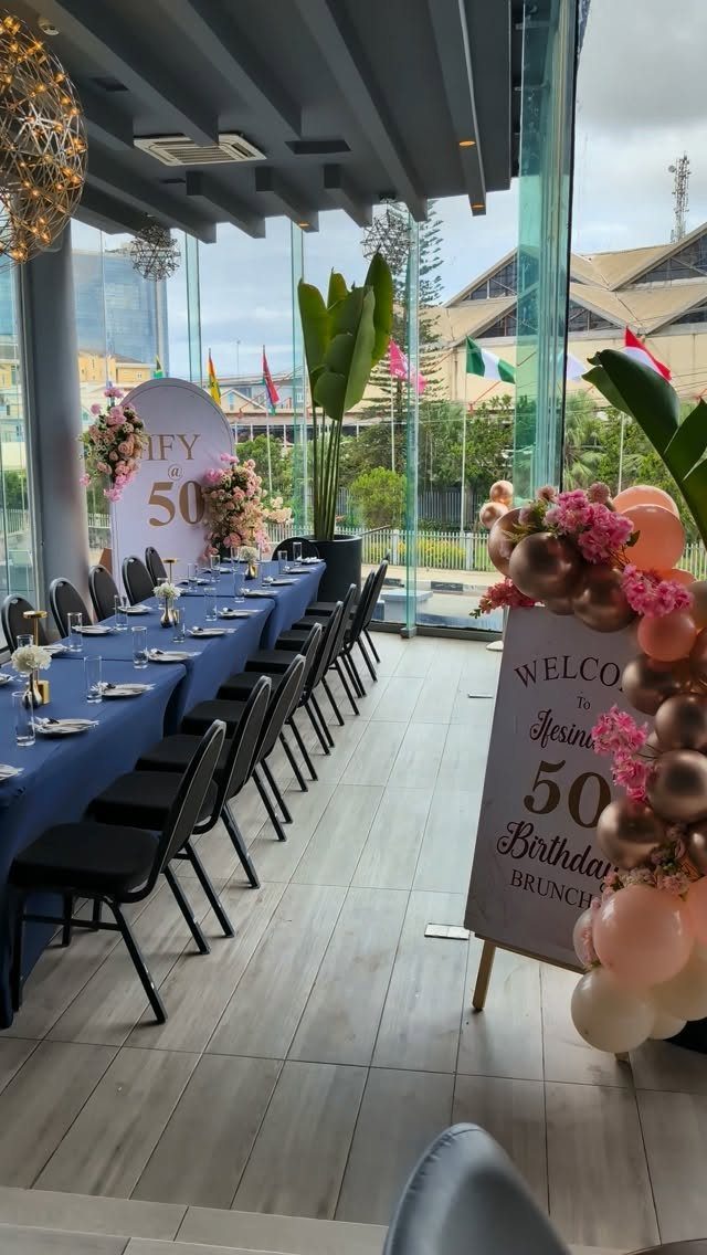 Long dining table with blue cloth and balloons for a 50th birthday brunch.