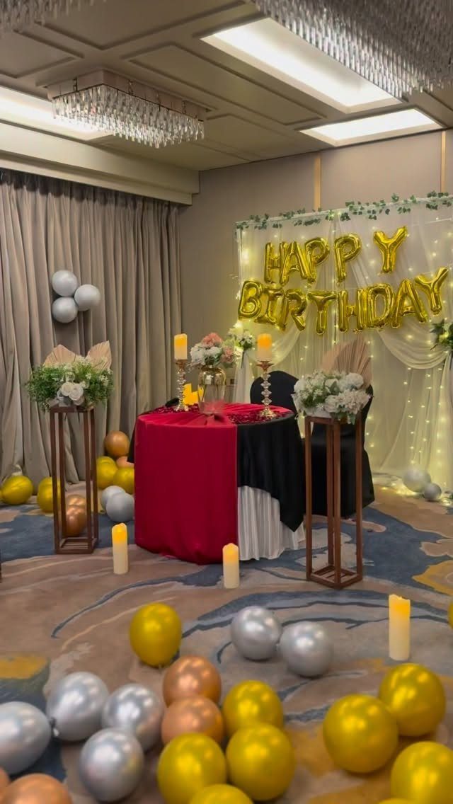 Birthday party setup in a hotel room with gold balloons and celebratory banner.