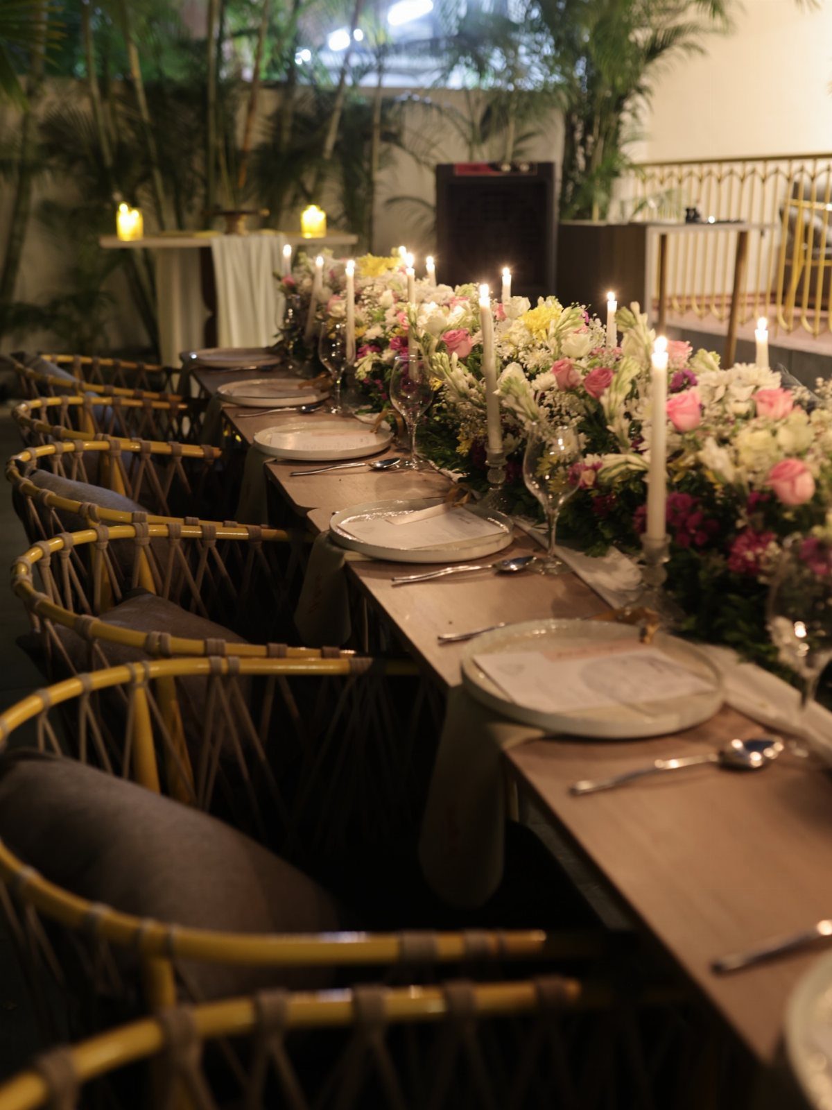Elegant long dining table with floral centerpieces and candles in a hotel setting