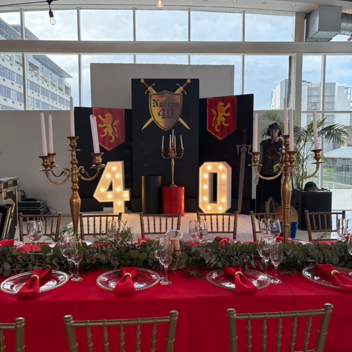 Medieval themed dinner table with red linens and large illuminated number 40 backdrop