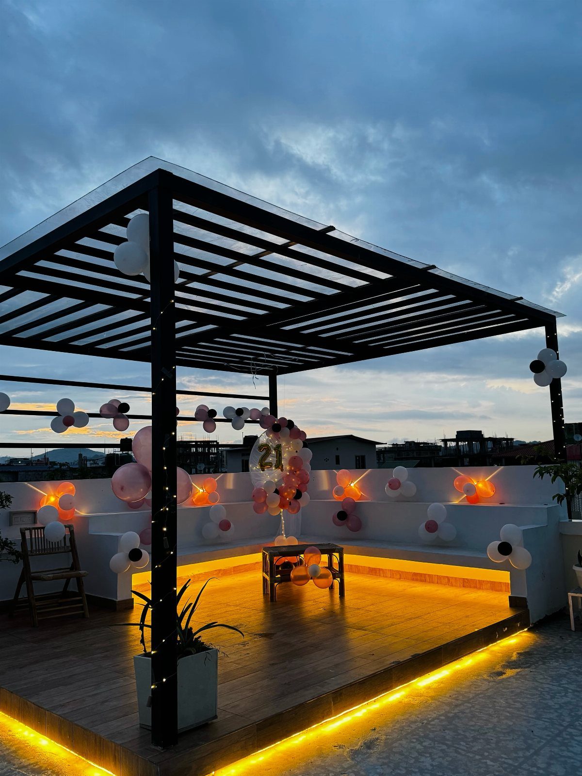 Rooftop patio decorated with pink and white balloons under a black metal pergola.
