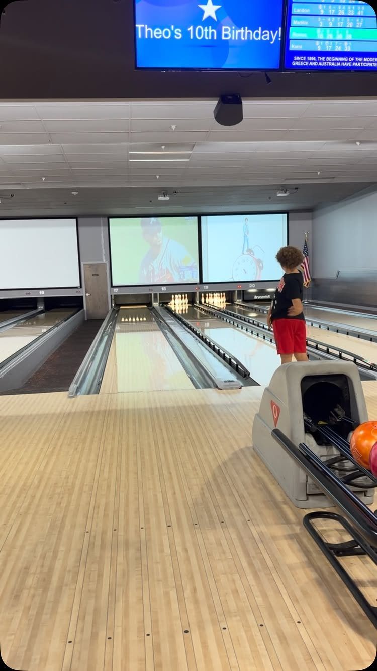 Young boy standing on a bowling lane during a 10th birthday party celebration.