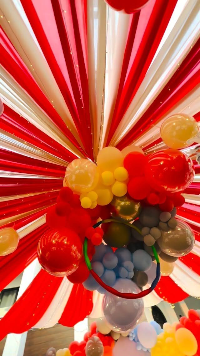 Red and white fabric ceiling streamers with a colorful balloon cluster decoration.