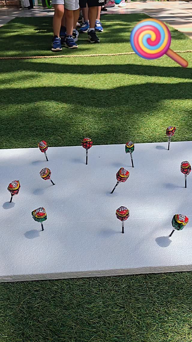 Colorful lollipops stuck in a white foam board on a green lawn.